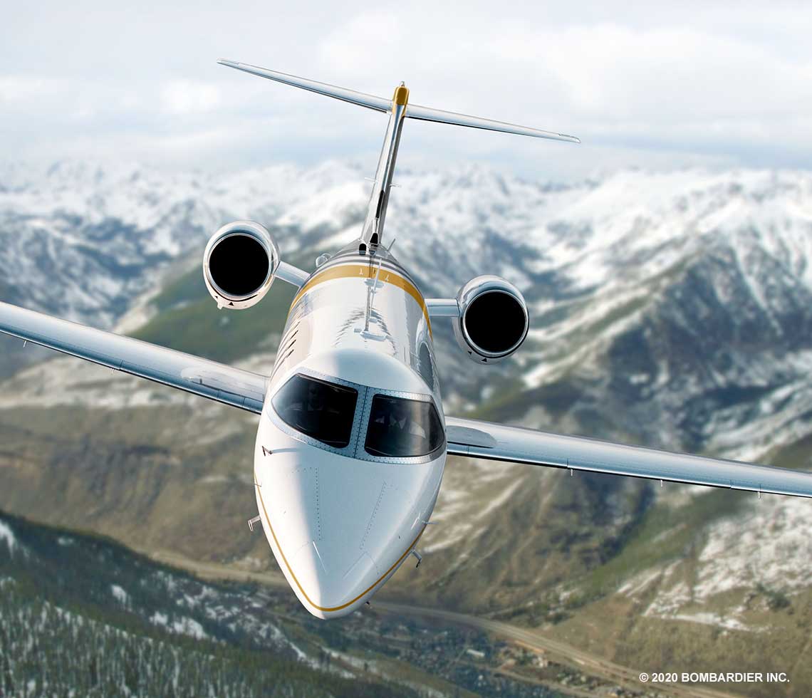 Learjet 75 private jet charter flying over snow covered valley