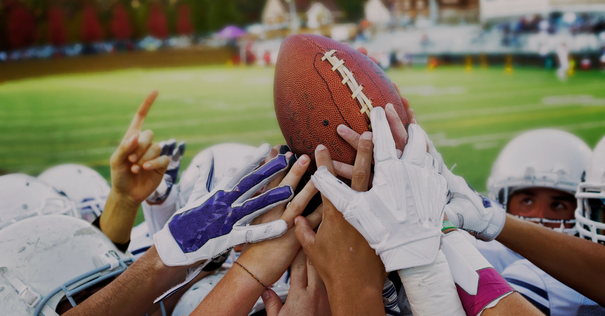 American football plays holding ball on pitch