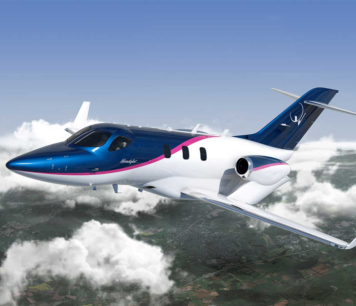 HondaJet aircraft flying in clouds with fields below