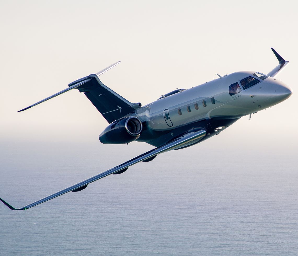 Embraer Legacy 450 private jet flying over sea